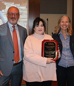 Jayne Thompson with award plaque standing alongside provost and president