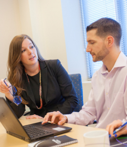 two people are talking, one of them is using a laptop