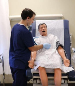 a nursing student working on a dummy patient in the simulation lab