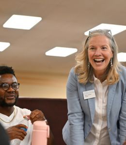 President Robertson talking and smiling, with a student off to her side doing the same.