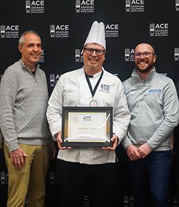 Chef Matt Clarke stands with two other people holding his silver award