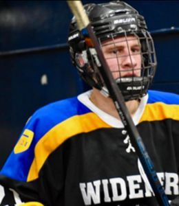 Jimmy Wynes, hockey player in Widener uniform, helmet on, holding stick