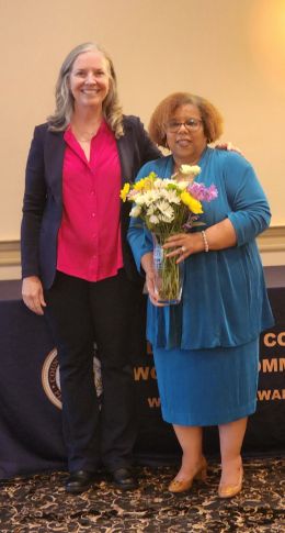 Micki Davis holding flowers standing alongside President Stacey Robertson at the award event.