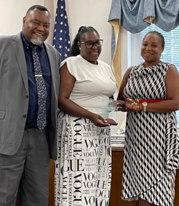 Three people pose for a photo with an award