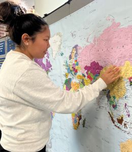 Student pushing a pin into a world map