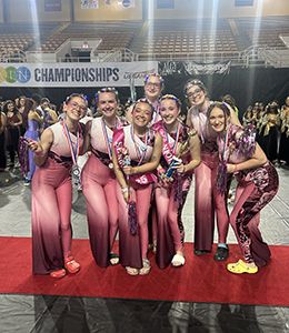 Seven members of the winter guard dressed in idential pink costumes