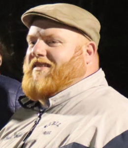 Photo of Andrew Burkhardt wearing a brown cap and jacket
