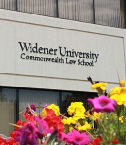 A building facade reads Widener University Commonwealth Law School. Beautiful flowers can also be seen.