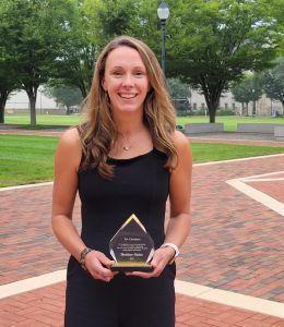 Heather Meier standing outdoors holding a glass trophy