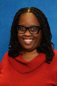Headshot of professor Keeshea Turner on a blue textured background