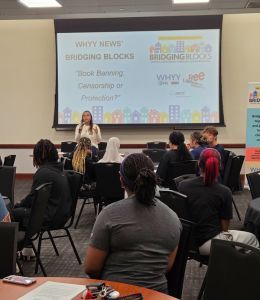 People seated in a room with a screen showing Bridging Blocks at the top, behind them