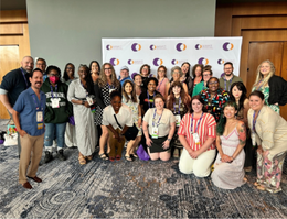 A group of faculty, students and alumni pose for a photo at a conference. 