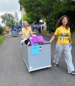 President Stacey Robertson pushing a cart loaded with a student's belongings, led by a volunteer helper