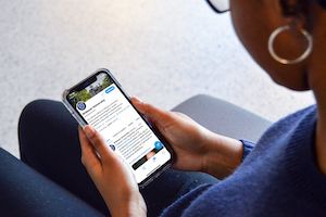 student looks at social media newsfeed on phone