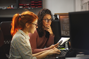 Two computer programmers working on a project in a computer lab