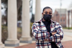 Student wearing a mask stands on campus