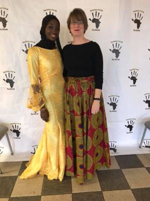 Fanta Koita in a yellow dress and black head scarf and Professor Stephanie Schechner in a red and yellow dress pose together