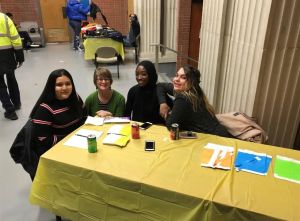 Three students and one professor sit together at a yellow table