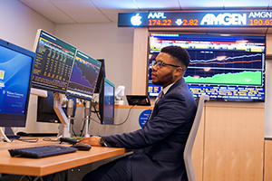 Student in Widener finance lab on computer with stock ticker in the background