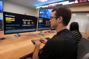 Student on a desktop computer in Widener's finance lab with a scrolling stock ticker in the background