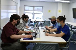 A group of civil engineering students diligently work on the laptops during a team meeting.