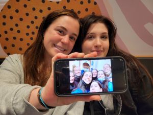 Two female students holding up a cell phone showing off a photo on the screen.