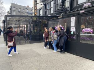 Student taking a photo of friends outside a restaurant in New York City.