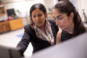 A biomedical engineering female professor and student review data on a computer screen.