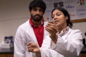 Tissue samples can be seen in a glass plate as a professor and student examine it under the light.