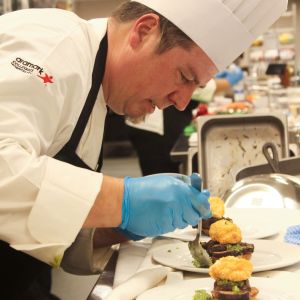 Widener Dining Executive Chef Matthew Clarke leaning over a plate of food, preparing it.