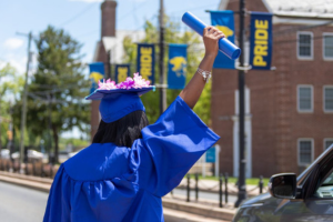 A female graduate holds her diploma tube up the air after crossing stage.
