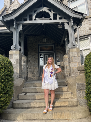 Emily Sockel poses in a white dress in front of the entrance of a building