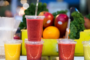 A collection of smoothies against a background of fresh fruits and vegetables