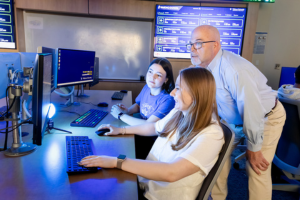 Two students are mentored by a faculty member in the finance lab on Widener University's campus.