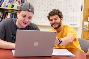 one male student advises another male student working on a computer at widener university