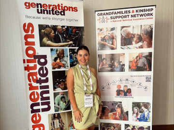 Jess Mereshensky poses in a green dress in front of conference banners