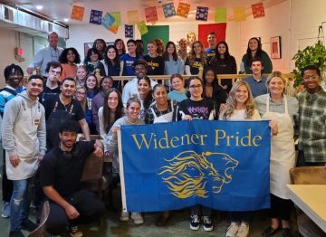 Students pose with Chef Cristina Martinez holding a Widener University flag