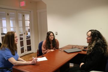 Deb McCracken speaks with students at a desk