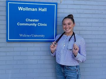 Taylor Wise poses in front of the Chester Community Clinic with her stethoscope draped around her neck.