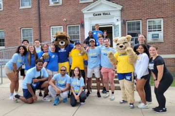 Student volunteers pose on the steps of Cann Hall with the mascots welcoming new students to campus.