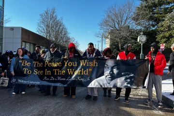 Students hold the MLK banner that reads "be the peace you wish to see in the world."