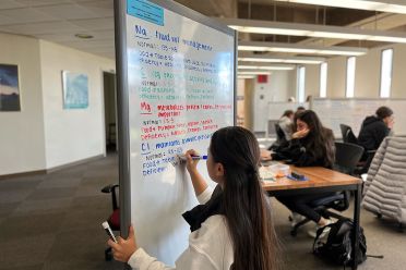 Student uses color markers to write on a whiteboard in the library