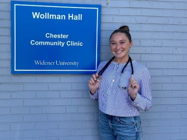 Taylor Wise poses in front of the Chester Community Clinic with her stethoscope draped around her neck.