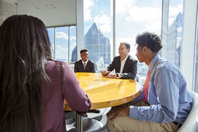 Student and alum sitting around a table at Comcast building