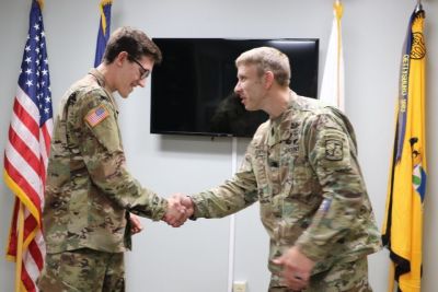 The leader of ROTC shaking a cadet's hand.