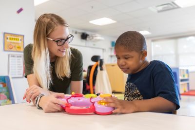 special education teacher working with a student in a classroom