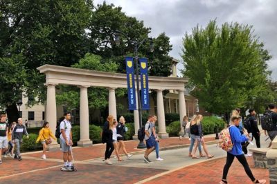 Students walk on campus past We're All Widener banners