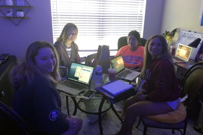Four students sitting around a table at their home learning pod space