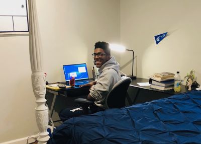 Student sitting at a desk in his bedroom