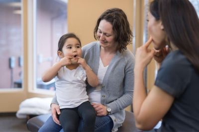 Speech=language pathologists works with a young child